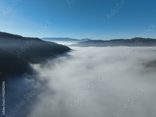 Fototapeta Naklejka Na Ścianę i Meble -  Aerial View. Flying over the high mountains in beautiful clouds. Aerial Drone camera shot. Air pollution clouds over Sarajevo in Bosnia and Herzegovina. 