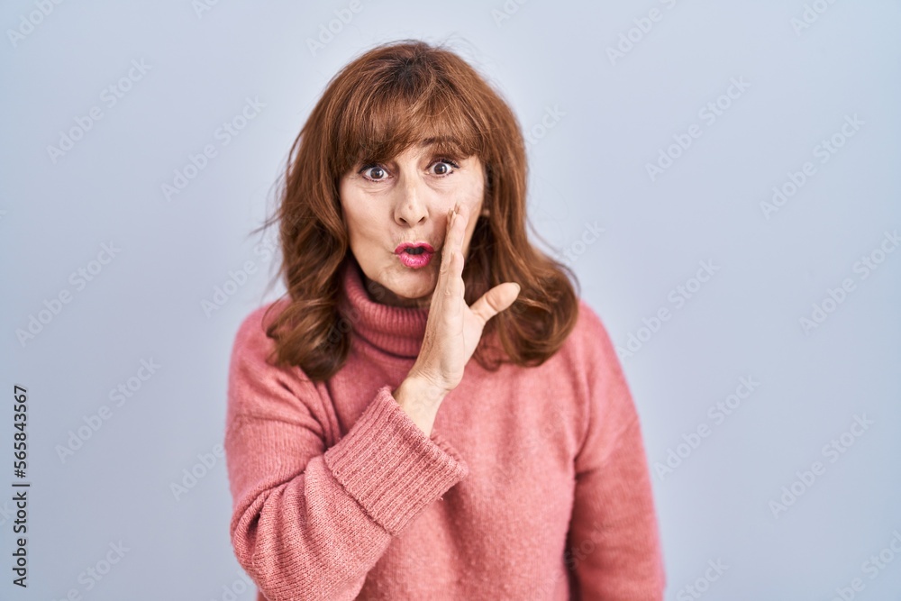 Middle age hispanic woman standing over isolated background hand on mouth telling secret rumor, whispering malicious talk conversation Middle age hispanic woman standing over isolated background hand on mouth telling secret rumor, whispering malicious talk conversation
