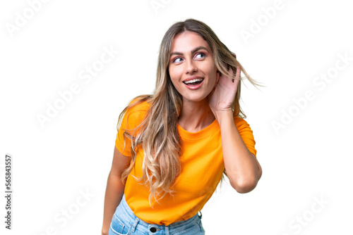 Young Uruguayan woman over isolated background listening to something by putting Fototapet