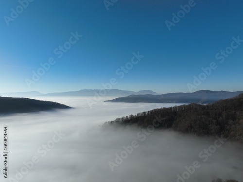 Aerial View. Flying over the high mountains in beautiful clouds. Aerial Drone camera shot. Air pollution clouds over Sarajevo in Bosnia and Herzegovina. 