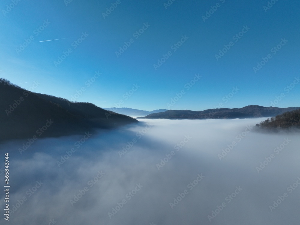 Fototapeta premium Aerial View. Flying over the high mountains in beautiful clouds. Aerial Drone camera shot. Air pollution clouds over Sarajevo in Bosnia and Herzegovina. 