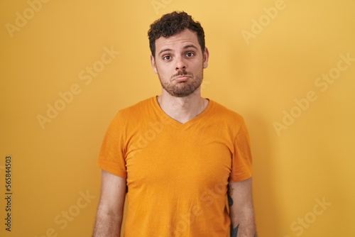 Young hispanic man standing over yellow background depressed and worry for distress, crying angry and afraid. sad expression.