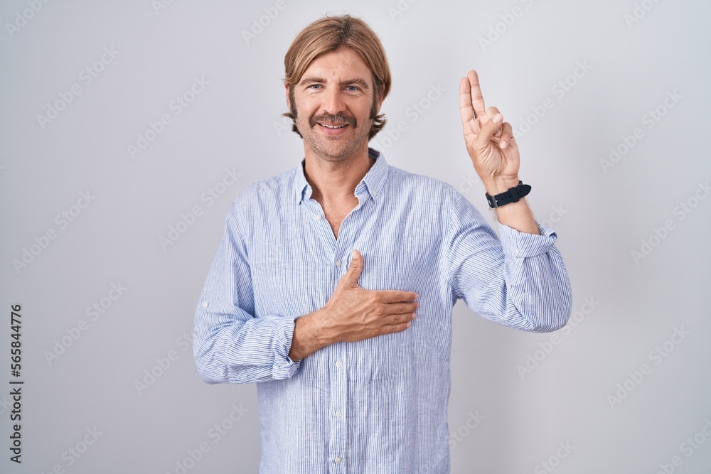 © Krakenimages.com - Caucasian man with mustache standing over white background smiling swearing with hand on chest and fingers up, making a loyalty promise oath