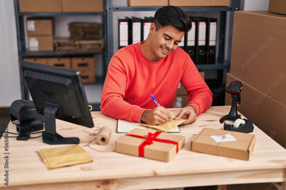 Young hispanic man ecommerce business worker writing on package at office Young hispanic man ecommerce business worker writing on package at office