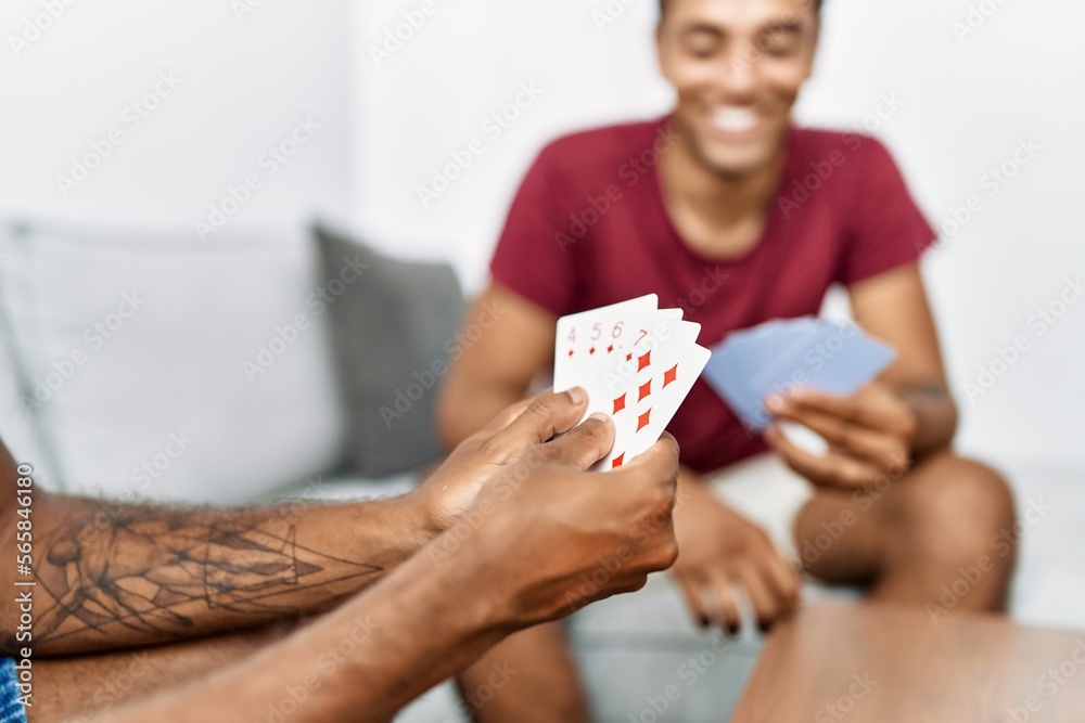 Two men friends playing poker cards sitting on sofa at home Two men friends playing poker cards sitting on sofa at home