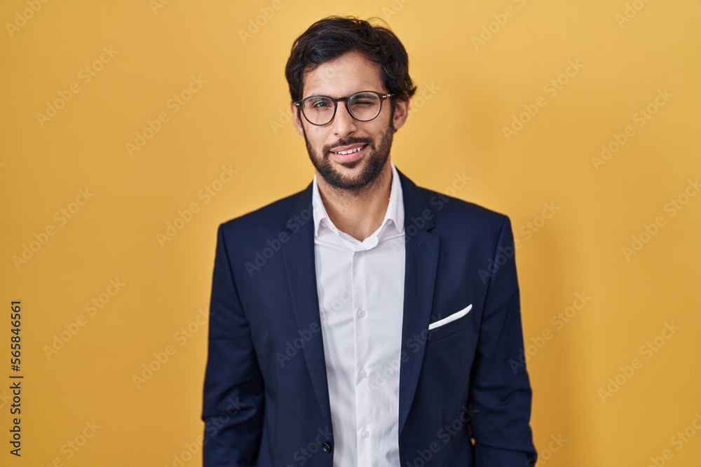 Handsome latin man standing over yellow background winking looking at the camera with sexy expression, cheerful and happy face. Handsome latin man standing over yellow background winking looking at the camera with sexy expression, cheerful and happy face.