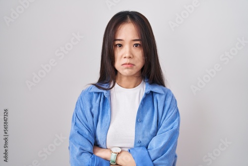 Young chinese woman standing over white background depressed and worry for distress, crying angry and afraid. sad expression. © Krakenimages.com