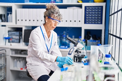 Middle age woman scientist mixing on bowl at laboratory photo