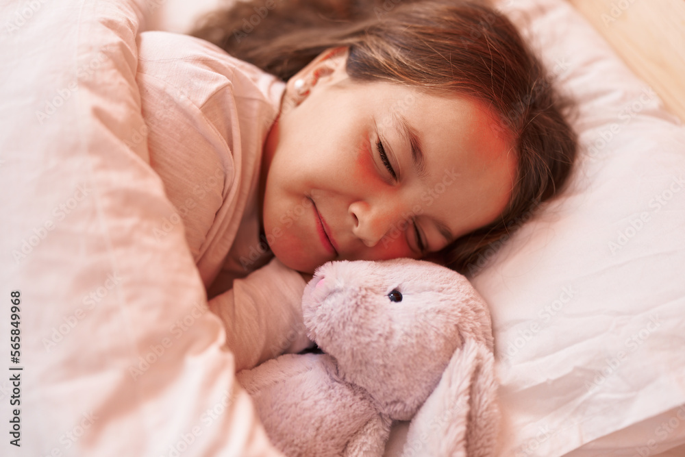 Adorable hispanic girl hugging rabbit doll lying on bed sleeping at bedroom Adorable hispanic girl hugging rabbit doll lying on bed sleeping at bedroom