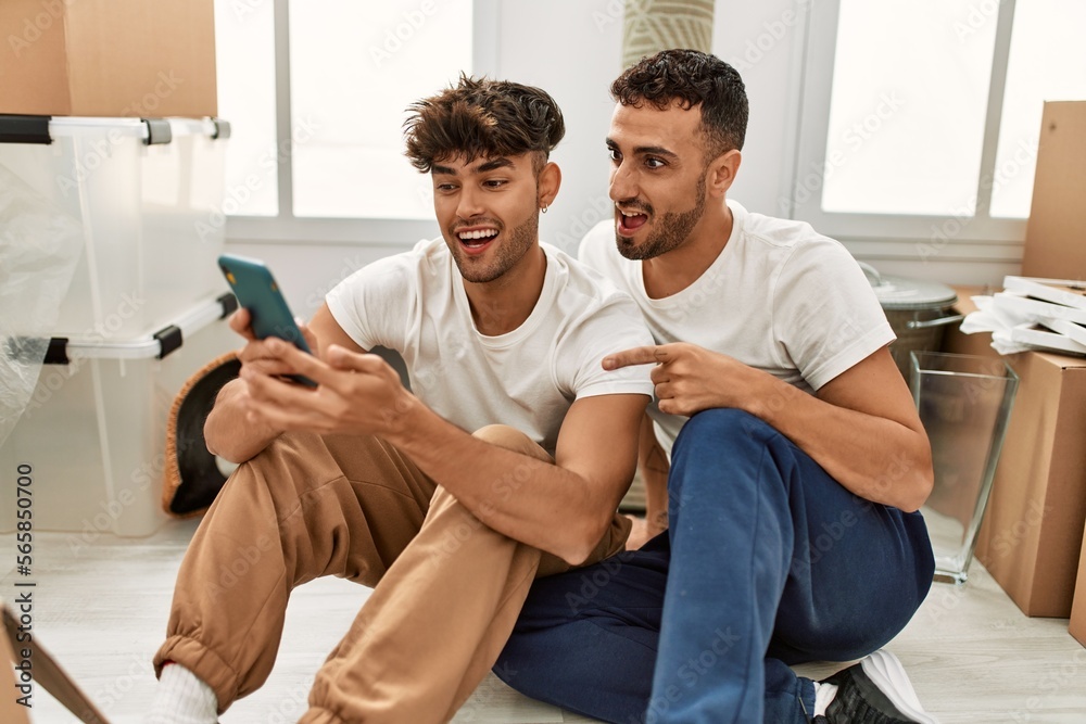 Two hispanic men couple smiling confident using smartphone at new home Two hispanic men couple smiling confident using smartphone at new home