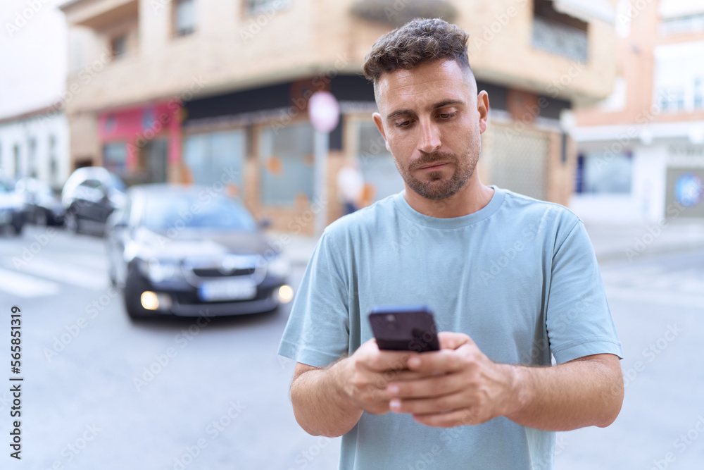 Young hispanic man using smartphone with serious expression at street Young hispanic man using smartphone with serious expression at street