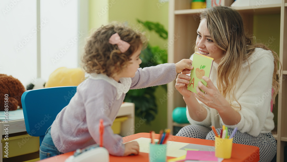Teacher and toddler sitting on table having language lesson at kindergarten Teacher and toddler sitting on table having language lesson at kindergarten