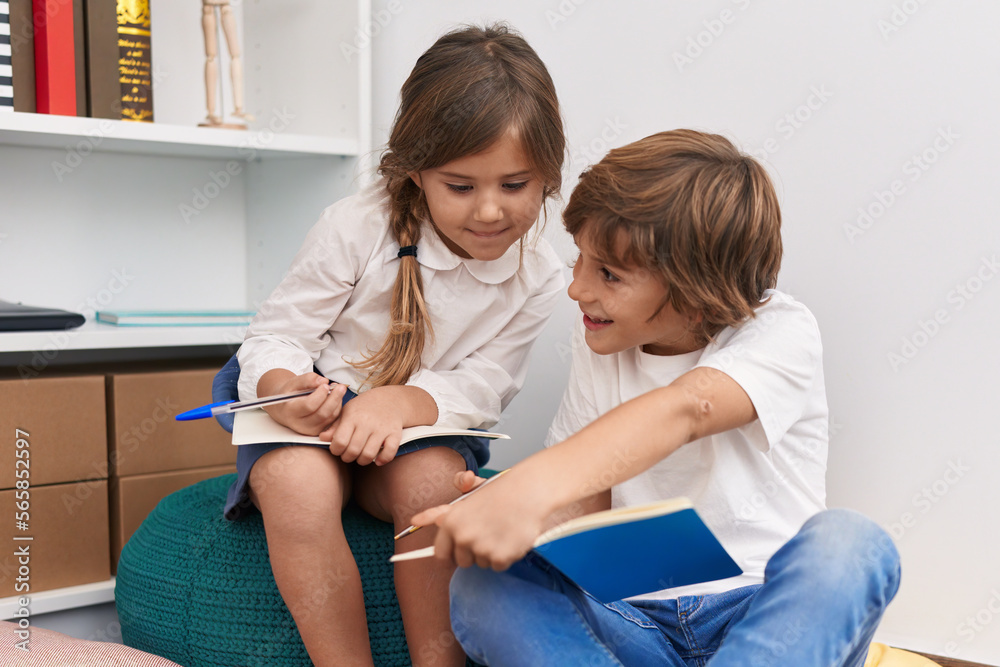 Fototapeta premium Brother and sister students writing on notebook studying at library school