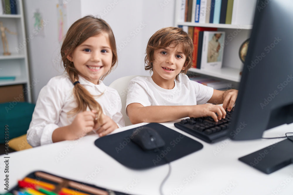 Brother and sister students using computer sitting on table at classroom Brother and sister students using computer sitting on table at classroom