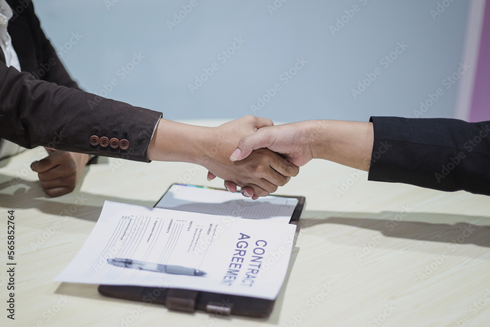 Close up of two businessman handshaking in office after contract agreement Close up of two businessman handshaking in office after contract agreement