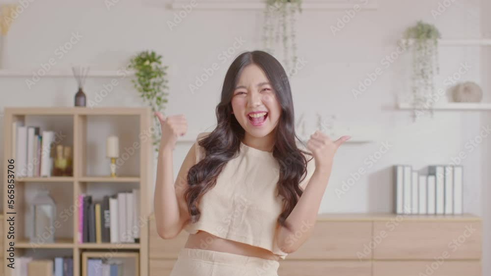 Beautiful young Asian woman showing thumbs up good gesture smile with positive emotional at home. Attractive female making finger thumbs up happiness and cheerful. Women lifestyle concept Beautiful young Asian woman showing thumbs up good gesture smile with positive emotional at home. Attractive female making finger thumbs up happiness and cheerful. Women lifestyle concept