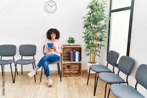 Young middle east woman using touchpad sitting on chair at waiting room