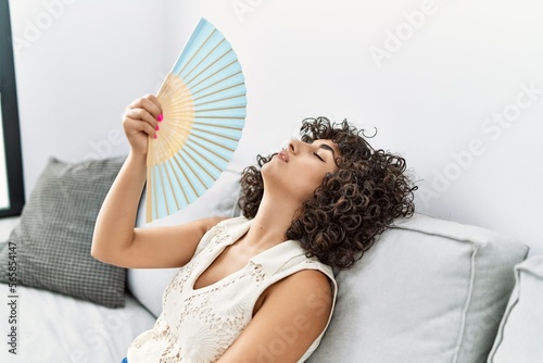 Young middle east woman desperate using hand fan at home photo