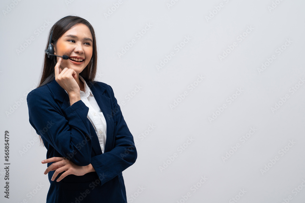 Beautiful Asian call center operator talking with customer using headset and microphone isolated on grey background. Beautiful Asian call center operator talking with customer using headset and microphone isolated on grey background.