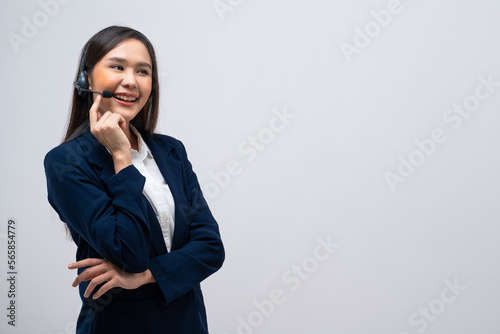 Beautiful Asian call center operator talking with customer using headset and microphone isolated on grey background.