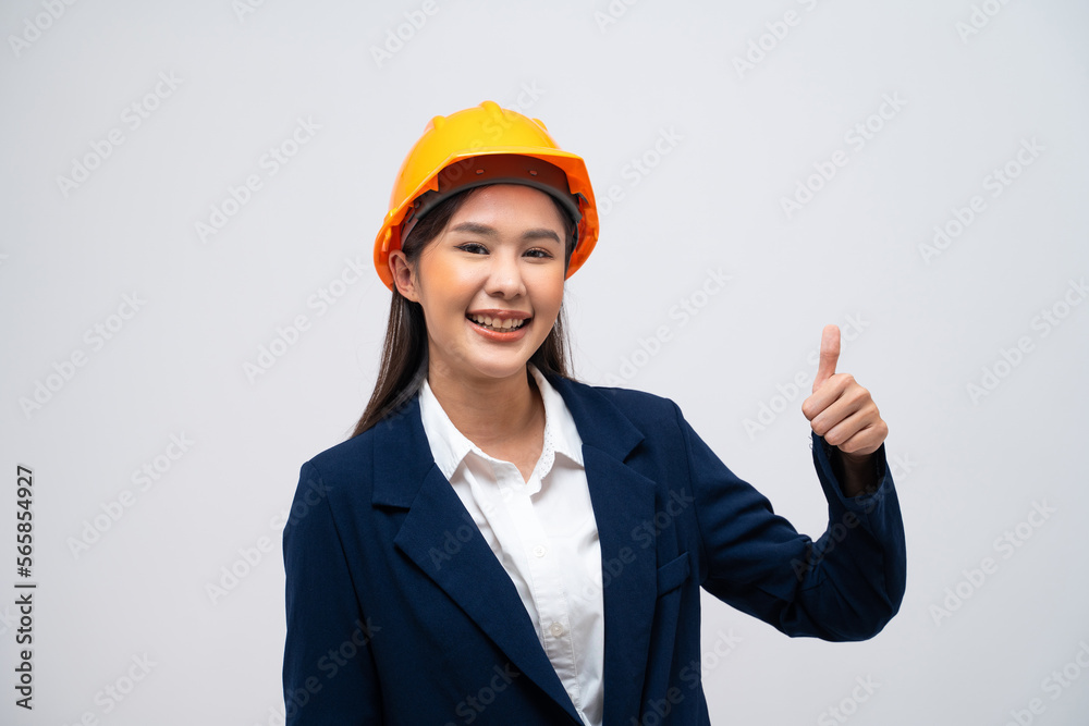 Portrait of Asian female engineer with hard hat posing show thumb up like gesture isolated on grey background. Portrait of Asian female engineer with hard hat posing show thumb up like gesture isolated on grey background.