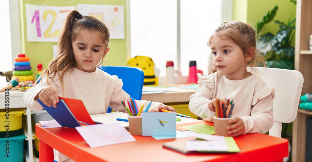 Fototapeta premium Two kids preschool students sitting on table drawing on paper at kindergarten