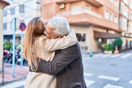 Middle age man and woman couple hugging each other standing at street