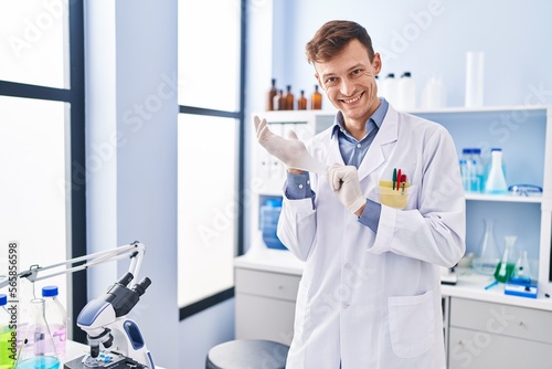Young man scientist smiling confident wearing gloves at laboratory