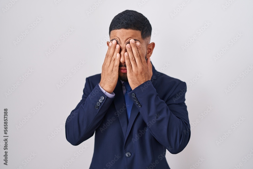 Young hispanic man wearing business suit and tie rubbing eyes for fatigue and headache, sleepy and tired expression. vision problem Young hispanic man wearing business suit and tie rubbing eyes for fatigue and headache, sleepy and tired expression. vision problem
