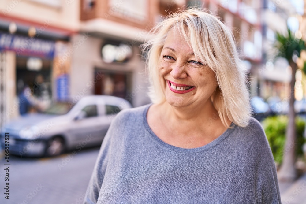 Middle age blonde woman smiling confident standing at street