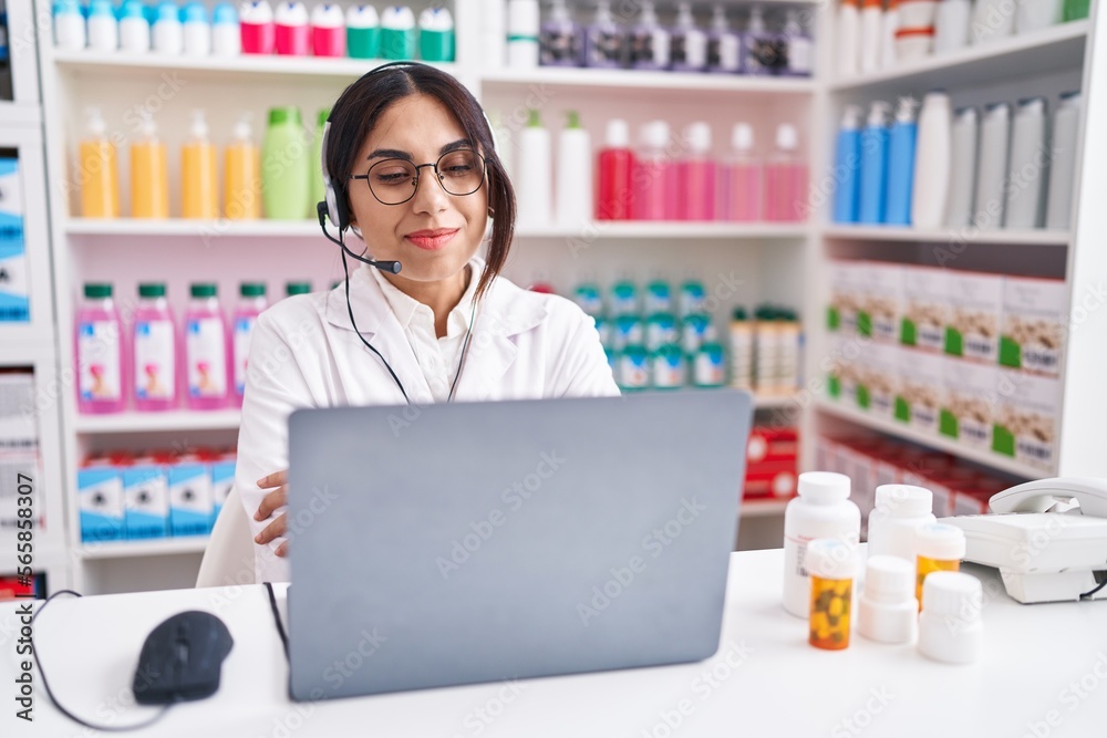 Young arab woman working at pharmacy drugstore using laptop happy face smiling with crossed arms looking at the camera. positive person.