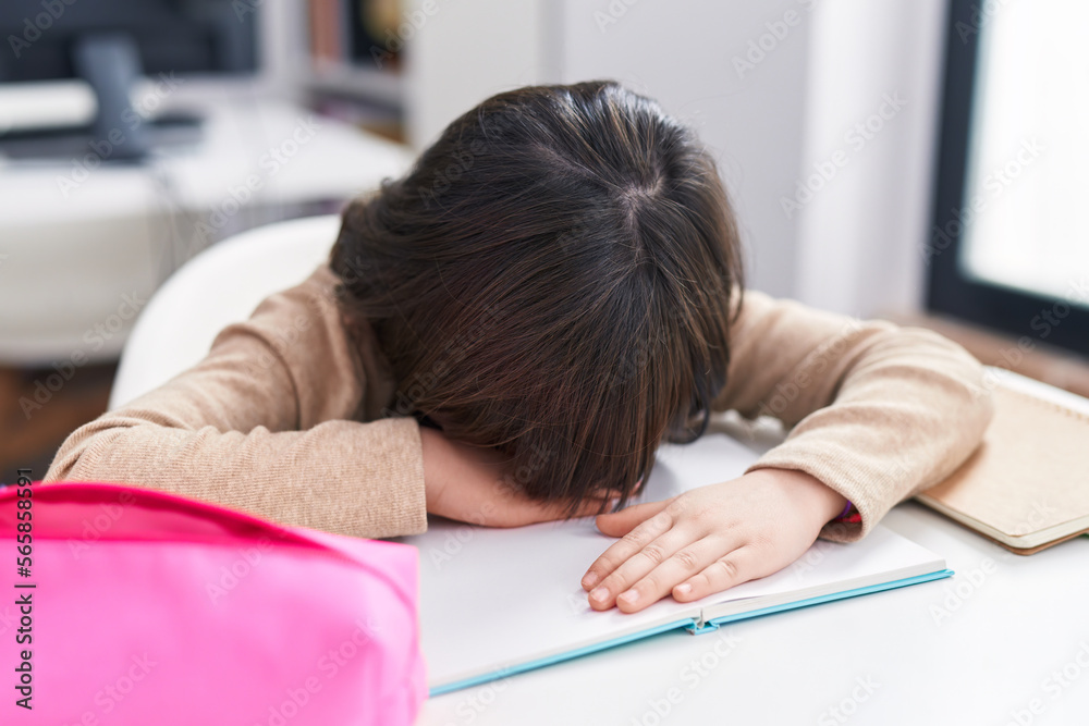 Adorable hispanic girl student stressed leaning on book at classroom Adorable hispanic girl student stressed leaning on book at classroom