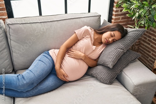 Young latin woman pregnant sleeping on sofa at home