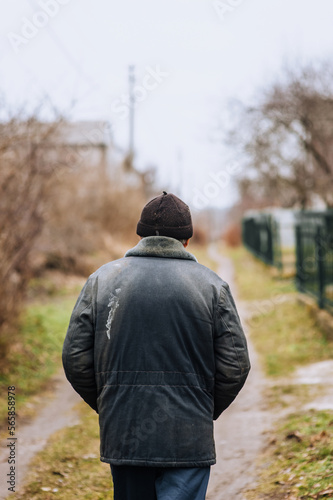 Konstfotografi A lonely man in dirty torn clothes, a beggar tramp, an old bum walks on the street in search of food and shelter