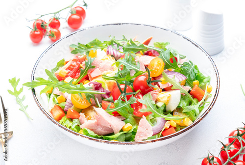 Fish tuna and fresh vegetables salad with cherry tomatoes, red onion, eggs, corn, paprika, lettuce, radicchio and arugula. White table background, top view