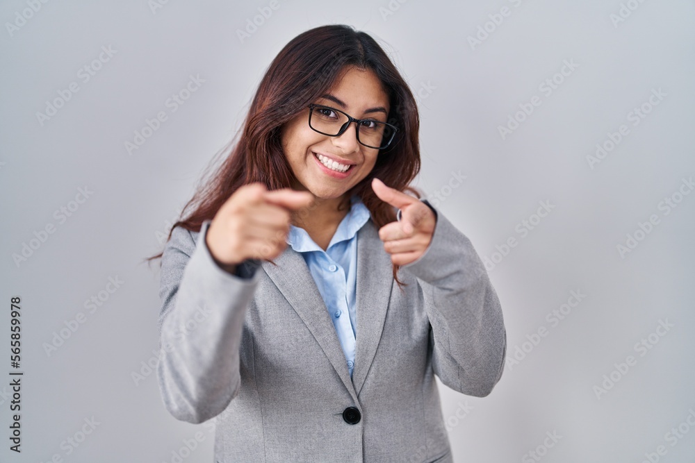 Hispanic young business woman wearing glasses pointing fingers to camera with happy and funny face. good energy and vibes.