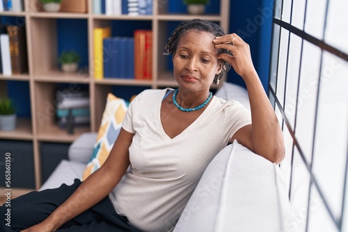 Middle age african american woman stressed sitting on sofa at home