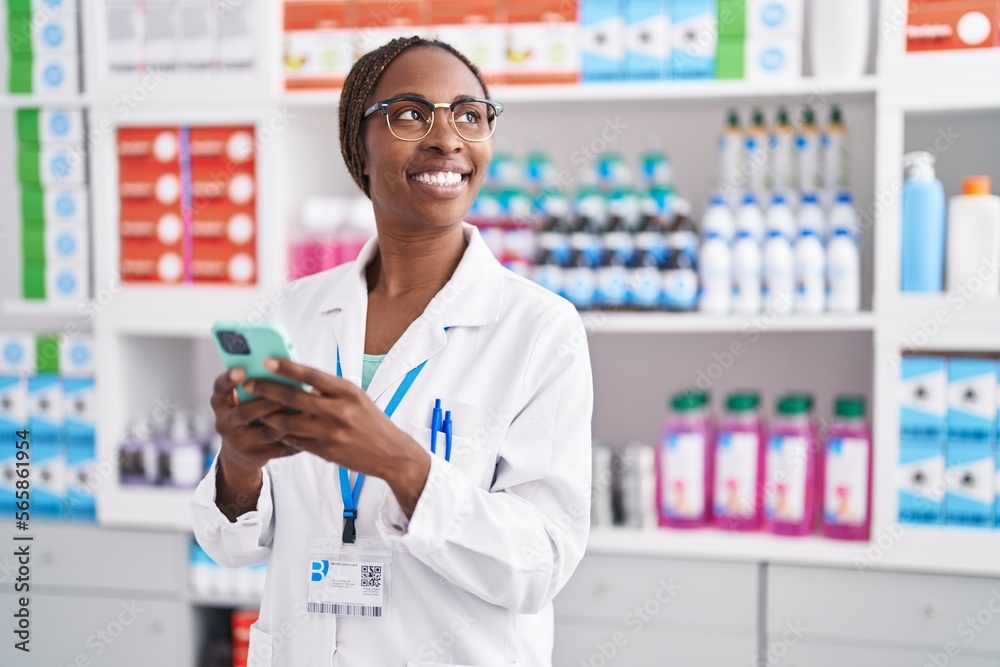 African american woman pharmacist using smartphone working at pharmacy