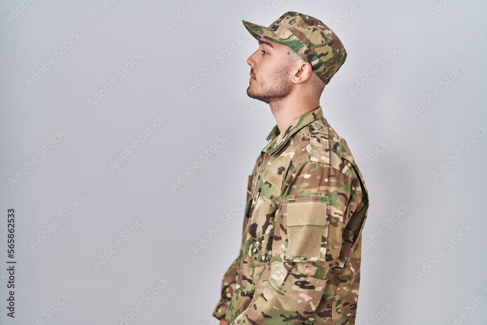 © Krakenimages.com - Young hispanic man wearing camouflage army uniform looking to side, relax profile pose with natural face with confident smile.
