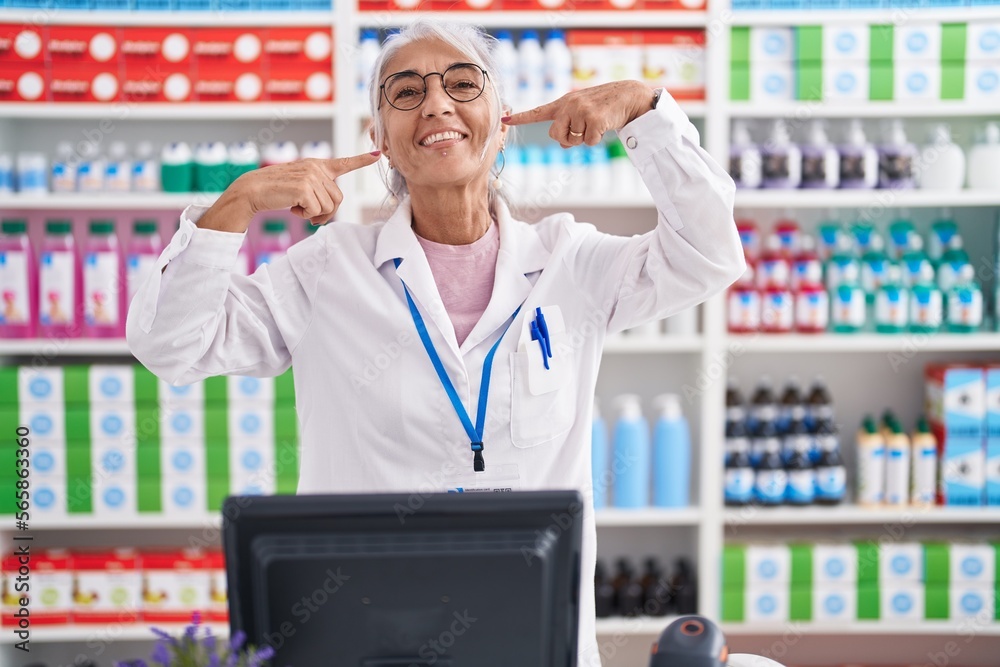 Middle age woman with tattoos working at pharmacy drugstore smiling cheerful showing and pointing with fingers teeth and mouth. dental health concept. Middle age woman with tattoos working at pharmacy drugstore smiling cheerful showing and pointing with fingers teeth and mouth. dental health concept.