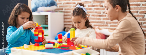 Group of kids playing with construction blocks sitting on table at kindergarten