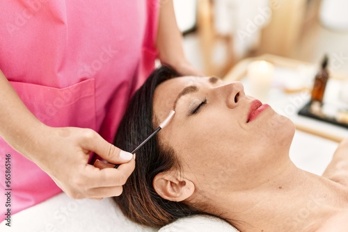 Middle age hispanic woman having eyebrows treatment at beauty center