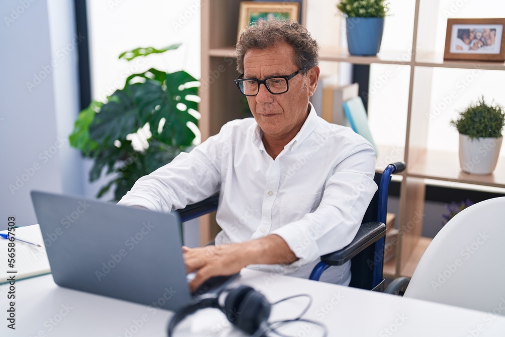 Middle age man sitting on wheelchair teleworking at home Middle age man sitting on wheelchair teleworking at home