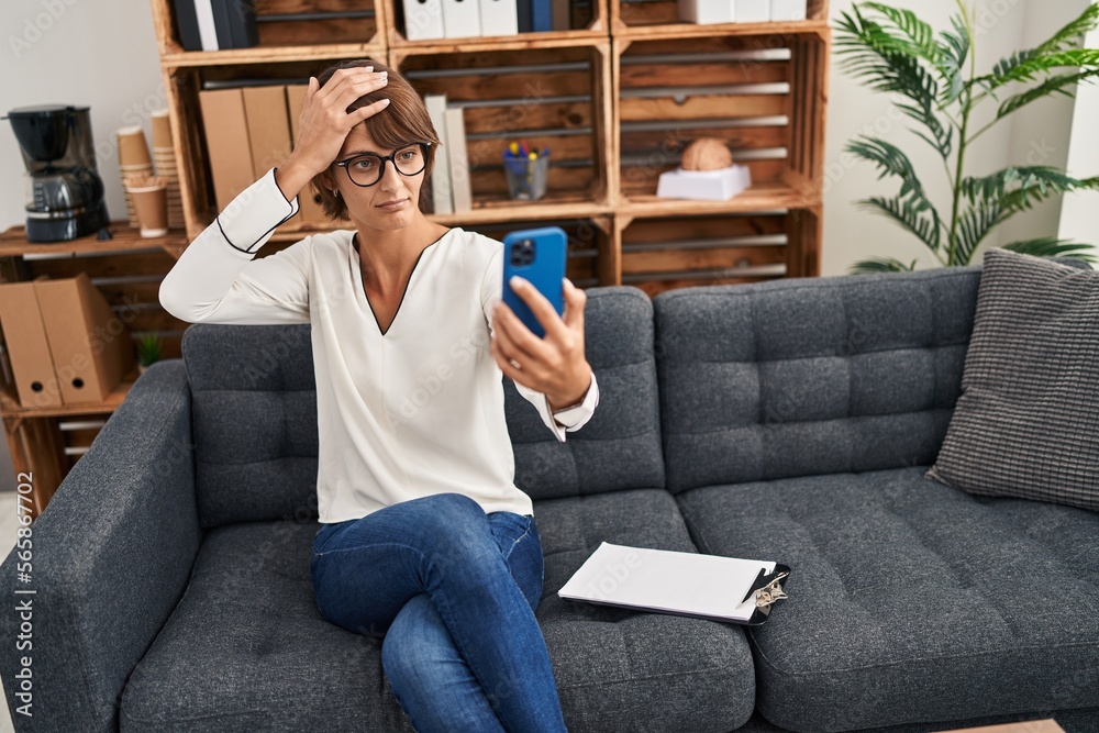 Brunette woman doing online session at consultation office stressed and frustrated with hand on head, surprised and angry face Brunette woman doing online session at consultation office stressed and frustrated with hand on head, surprised and angry face