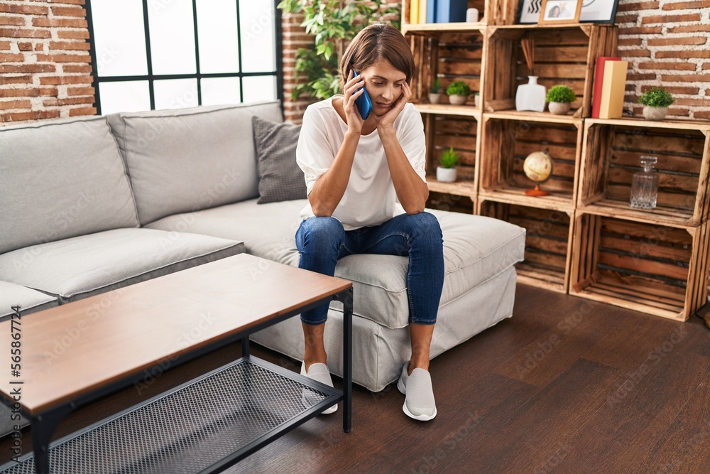 Young beautiful hispanic woman talking on smartphone with worried expression at home Young beautiful hispanic woman talking on smartphone with worried expression at home