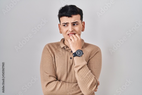 Non binary person standing over isolated background looking stressed and nervous with hands on mouth biting nails. anxiety problem. © Krakenimages.com