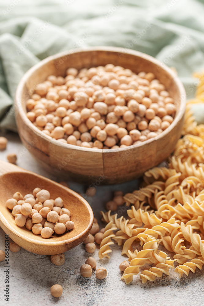 Chickpea bean fusilli pasta on a gray concrete background. Bowl with raw pasta and chickpea bean. Gluten free pasta.