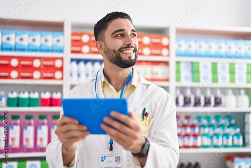 Foto Young arab man pharmacist using touchpad working at pharmacy