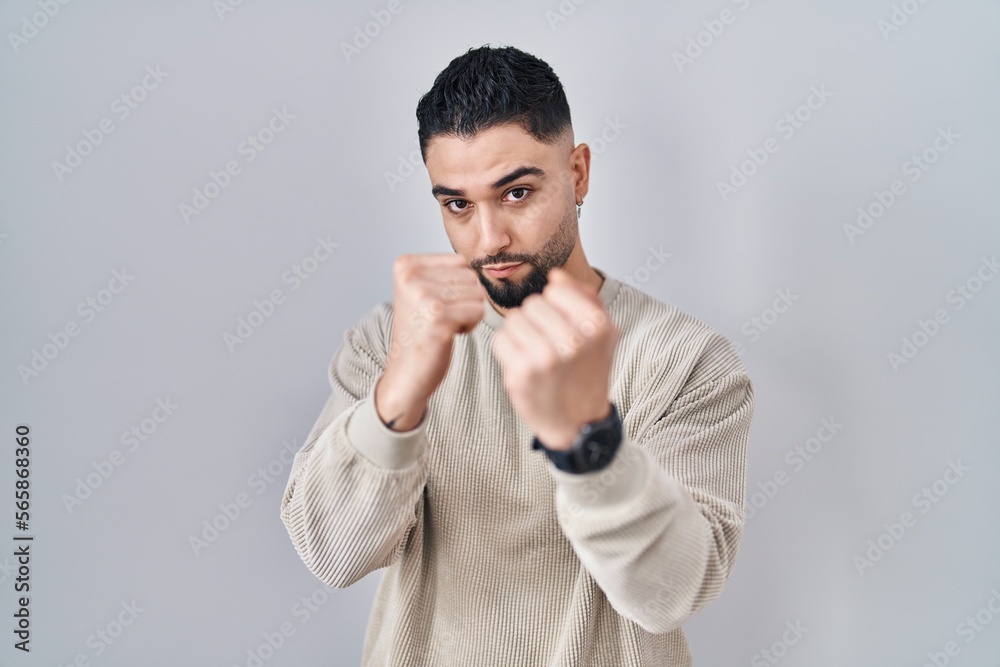 Young handsome man standing over isolated background ready to fight with fist defense gesture, angry and upset face, afraid of problem Young handsome man standing over isolated background ready to fight with fist defense gesture, angry and upset face, afraid of problem