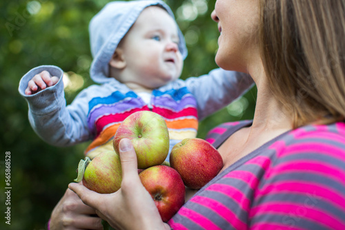 Mother holding baby and freshly picked apples, Parkdale, Oregon, USA photo